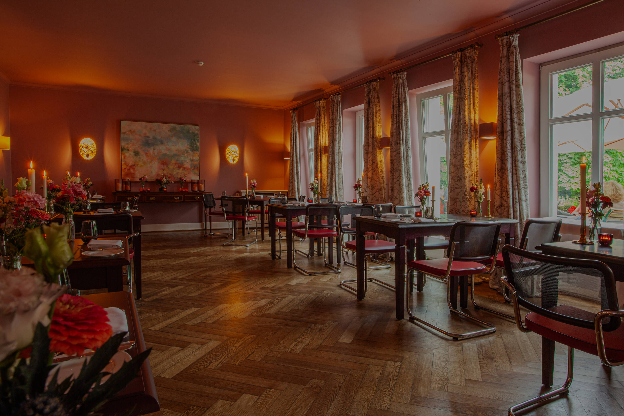 Ein Restaurant mit roten Stühlen, Holzboden und warmem Licht schafft eine behagliche Atmosphäre.