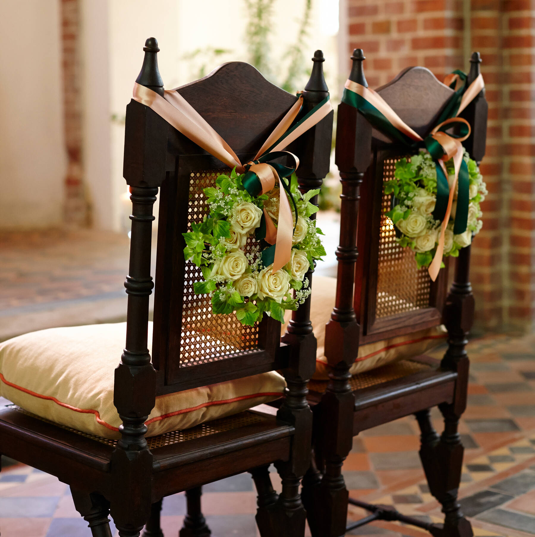 Romantische Stühle mit Blumengestecken und Schleifen, festlich geschmückt für eine Zeremonie in einer stilvollen Hochzeitslocation in Mecklenburg-Vorpommern.