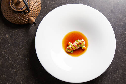 Ein kunstvoll angerichtetes Gericht mit Sauce in einem tiefen weißen Teller – moderne Küche mit Raffinesse.