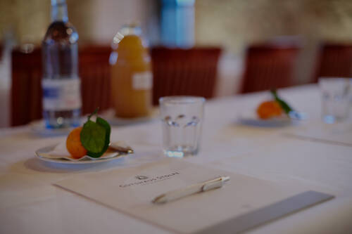 Ein heller Konferenztisch mit Wasserflaschen, Orangensaft, Mandarinen und Schreibunterlagen.