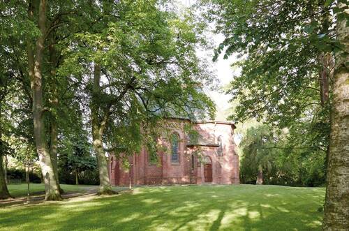 Eine historische Backsteinkapelle im grünen Park Stolpe.