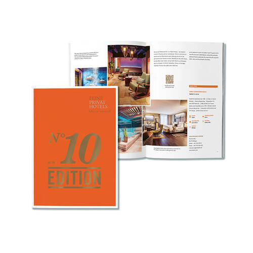 Ein aufgeschlagenes Hotelmagazin der 'Feinen Privat Hotels' und ein orangefarbener Umschlag mit Bildern stilvoller Hotelzimmer.