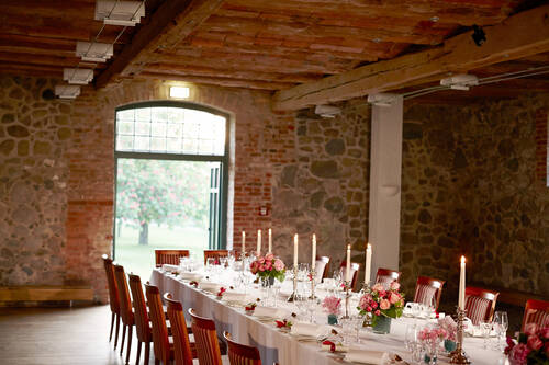 Eine Hochzeitstafel mit Kerzen und Blumenarrangements in stilvoller Hochzeitslocation Mecklenburg-Vorpommern.