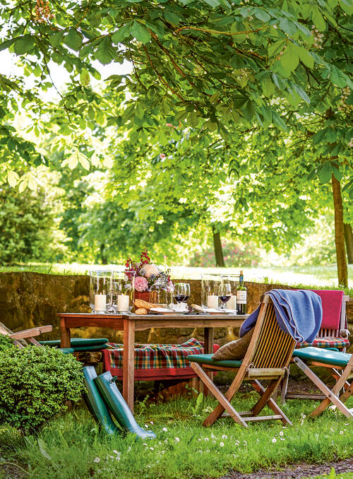 Ein romantisch gedeckter Tisch im Grünen mit Wein und Blumen – perfekte Kulisse für Feste in einer Eventlocation in Mecklenburg-Vorpommern.
