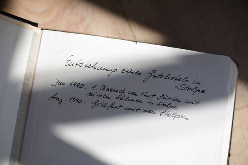 Eine aufgeschlagene Buchseite zeigt eine handgeschriebene Notiz über die Entstehung eines Gutshotels in Stolpe.