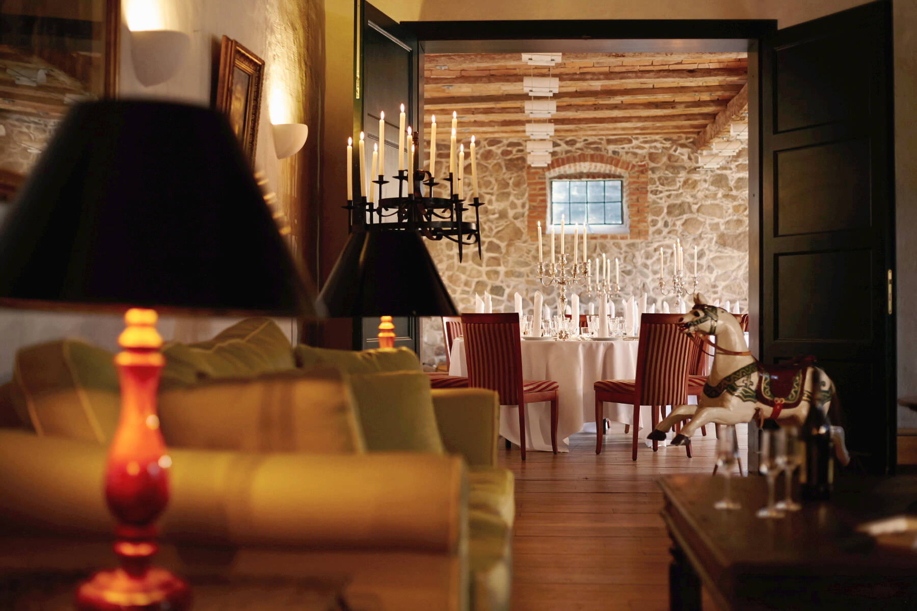 Ein edles Restaurant mit weißen Tischdecken, roten Stühlen und Kerzenleuchtern in einem Raum mit Natursteinmauern.