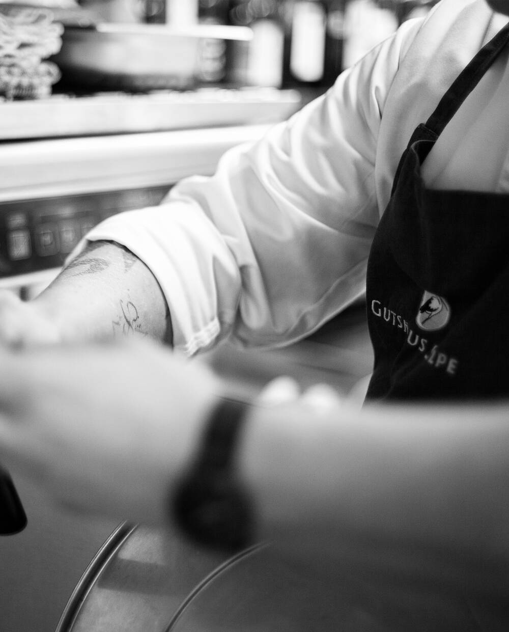 Ein Koch in Aktion mit einer Brand Schürze des Gutshaus Stolpe – leidenschaftliche Handwerkskunst und Qualität in einem Restaurant in Stolpe an der Peene.