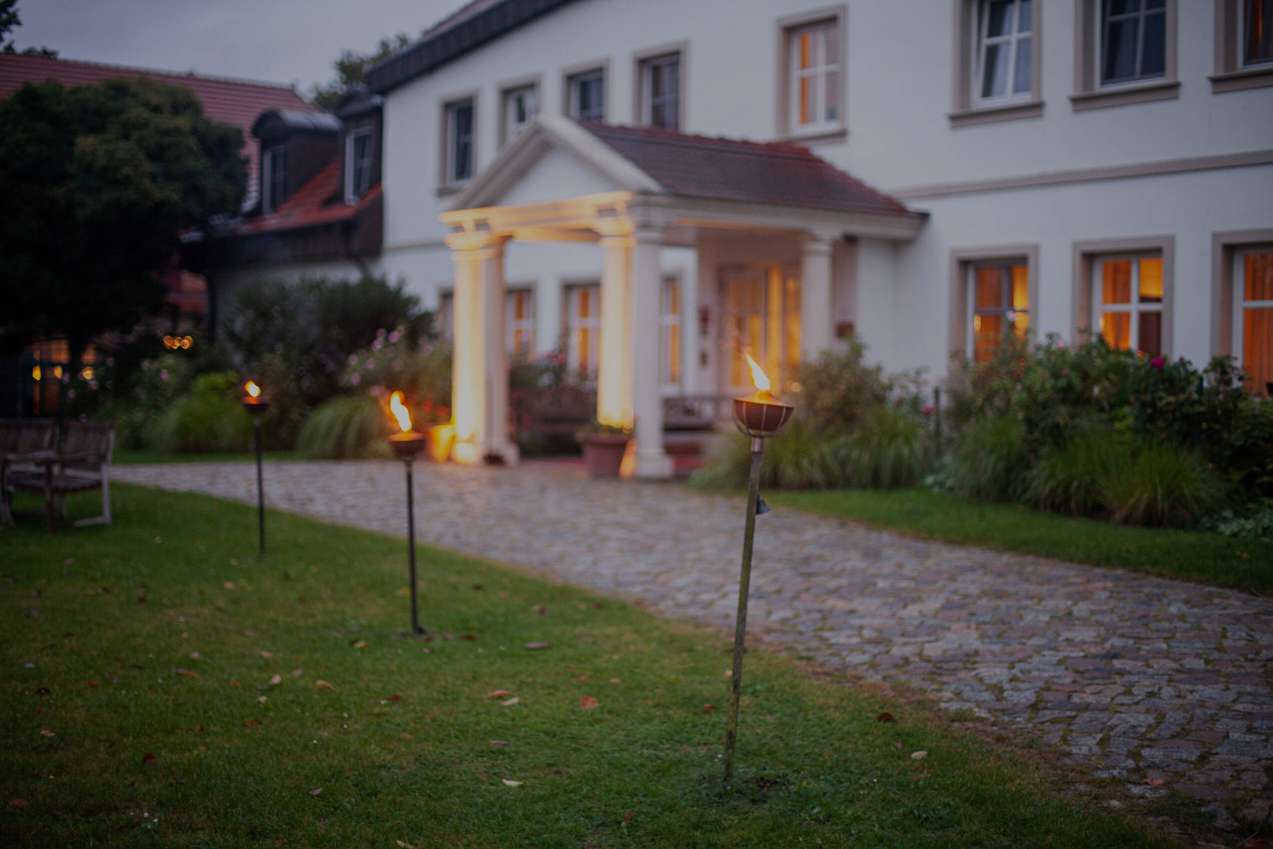 Das Gutshaus Stolpe im Abendlicht mit Fackeln – zauberhafte Atmosphäre in einem romantischen Hotel Norddeutschland.